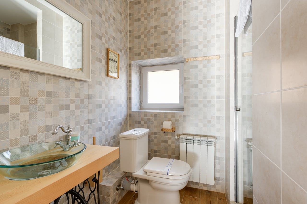 Bright bathroom featuring a contemporary glass sink, modern tiles, and natural light through the window.